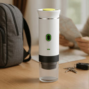 NØMA portable espresso maker in white on travel desk with map, backpack and keys.
